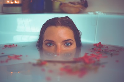 浴缸里的女人，红色的花瓣漂浮在水面上